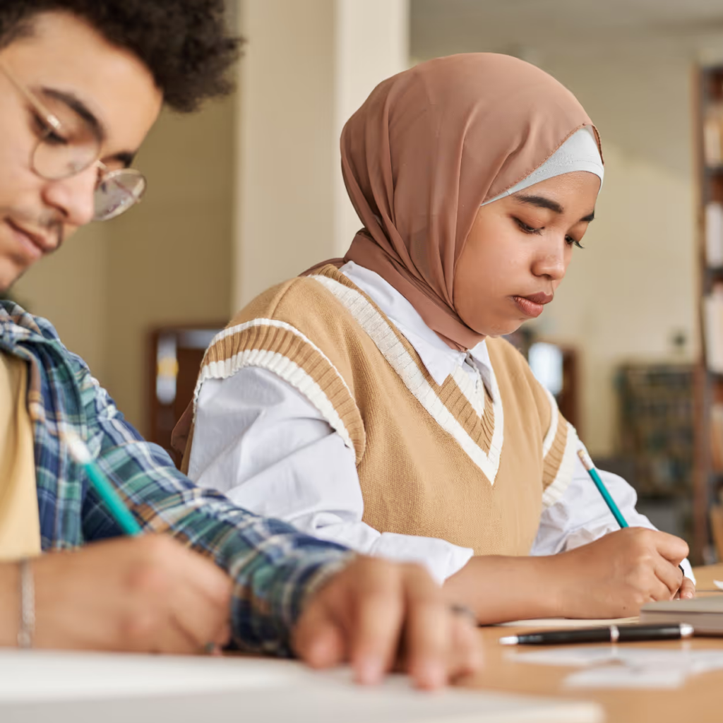 Twee studenten maken geconcentreerd aantekeningen tijdens een les