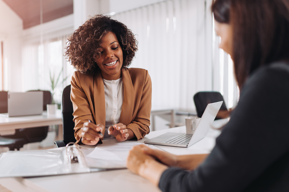 Twee vrouwen werken glimlachend aan een bureau