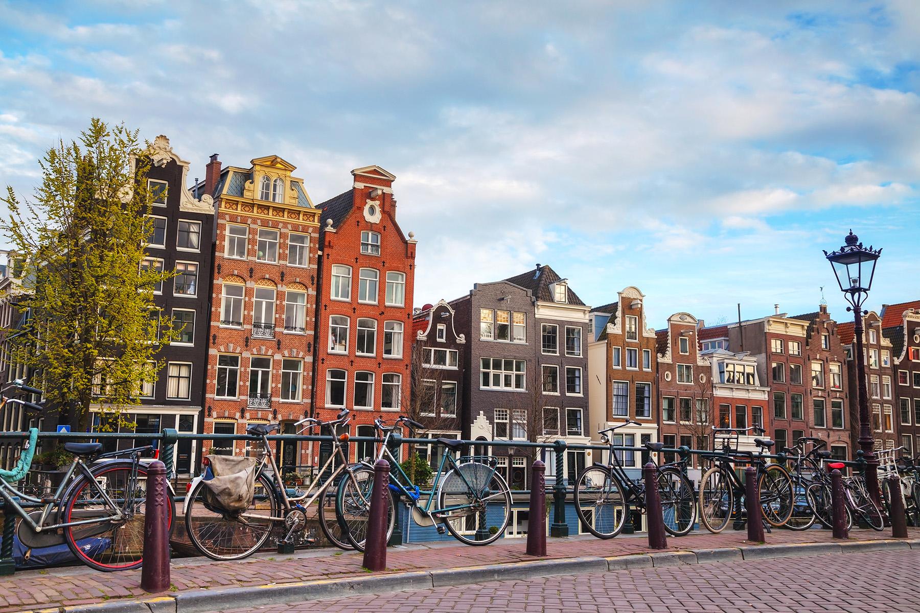 Historische Amsterdamse grachtenpanden met geparkeerde fietsen langs een brug