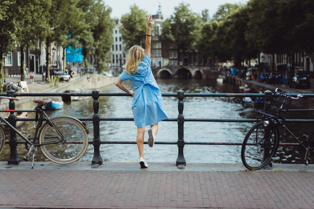 Vrouw in blauwe jurk staat op een brug in Amsterdam