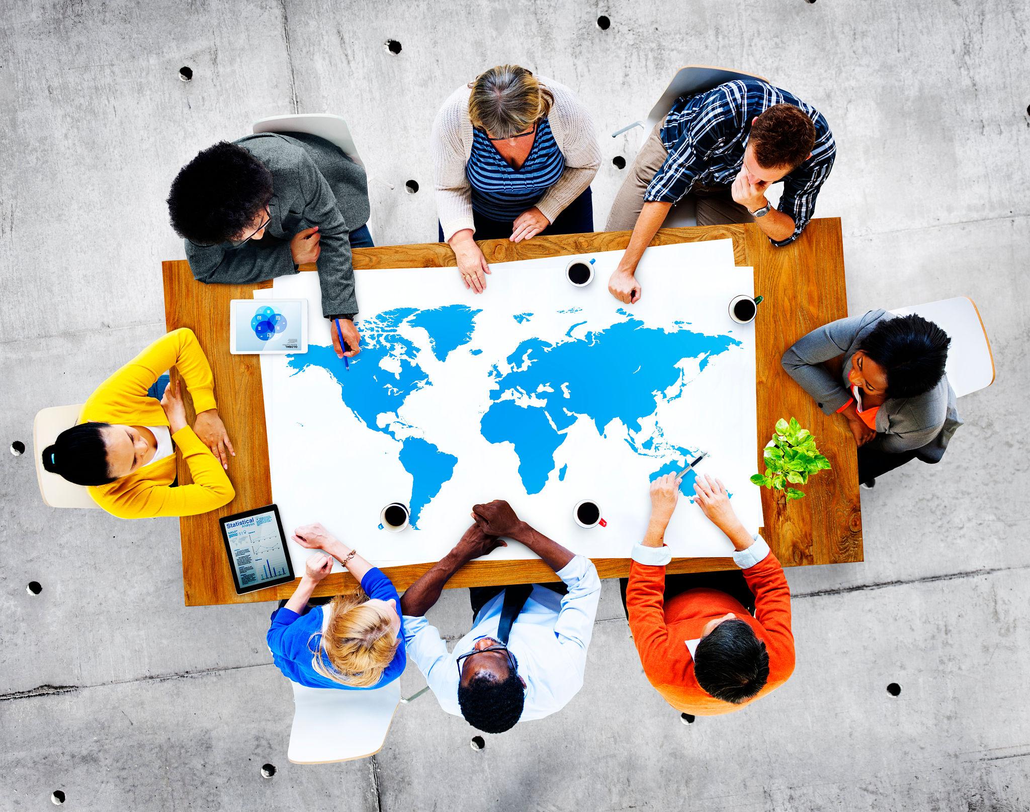 Bovenaanzicht van een divers team dat rond een tafel met een wereldkaart overlegt